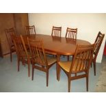 A RETRO TEAK EXTENDING DINING TABLE WITH EIGHT CHAIRS