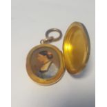 A PROFILE PORTRAIT MINIATURE SET IN A LARGE YELLOW METAL LOCKET, on suspension ring, height 6.25 cm