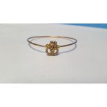 AN UNMARKED YELLOW METAL BANGLE, INTERTWINED HEARTS SET WITH SEED PEARLS. Approx. weight 5.3 g