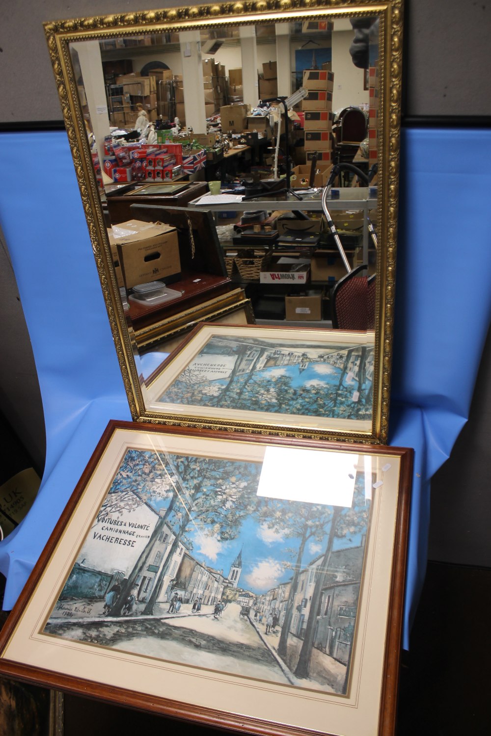 A GILT FRAMED MIRROR, 98 X 67 CM TOGETHER WITH A FRAMED AND GLAZED PRINT OF A STREET SCENE