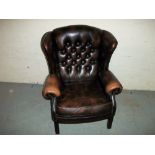 A BROWN LEATHER WING BACK CHAIR