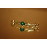 AN UNMARKED YELLOW METAL BAR BROOCH SET WITH POLISHED GREEN STONE
