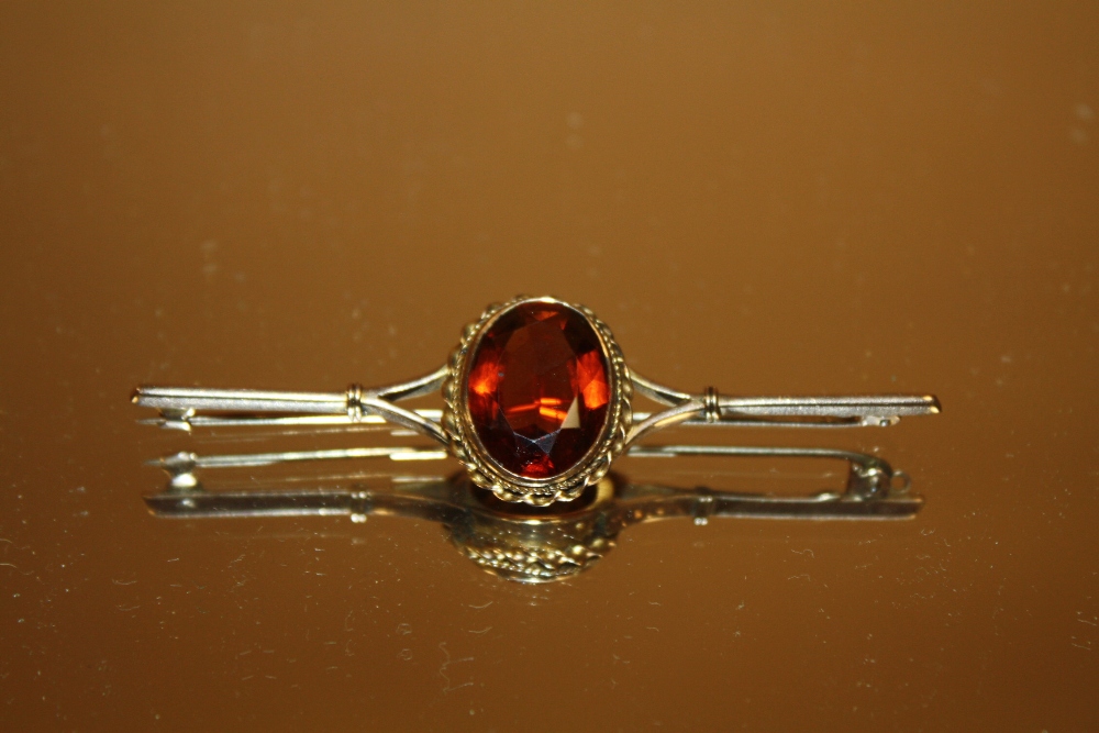 AN ANTIQUE 9CT GOLD BAR BROOCH SET WITH LARGE FACETED GEMSTONE