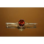 AN ANTIQUE 9CT GOLD BAR BROOCH SET WITH LARGE FACETED GEMSTONE