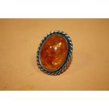 A LARGE SILVER MOUNTED AMBER RING