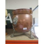 A COPPER TWIN HANDLED COAL BUCKET RAISED ON BRASS FEET