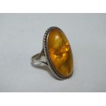 A LARGE SILVER MOUNTED AMBER RING