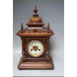 AN EARLY 20TH CENTURY WALNUT 'GREENWICH' MANTEL CLOCK BY W E WATTS, the architectural case topped