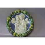 A CIRCULAR MAIOLICA PLAQUE DEPICTING MADONNA AND CHILDREN IN THE STYLE OF DELLA ROBIA, the central