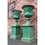 A LARGE PAIR OF ANTIQUE CAST IRON CAMPANA SHAPED URNS ON STANDS, each urn with twin handles,