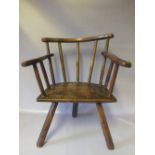 A CHILDS PRIMITIVE ELM STICKBACK ARMCHAIR, of naive construction, the curved top rail over a