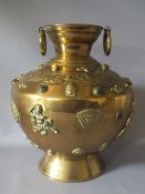 A DECORATIVE INDIAN BRASS VASE ON FOOTED BASE, of circular form, with raised and embossed mask,