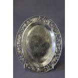 A SMALL OVAL WHITE METAL CARD TRAY, having Chinese style pierced border, on four bun feet, stamp