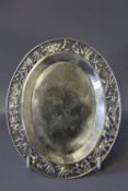 A SMALL OVAL WHITE METAL CARD TRAY, having Chinese style pierced border, on four bun feet, stamp