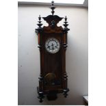 A LATE 19/EARLY 20TH CENTURY WALNUT VIENNA WALL CLOCK, the enamel dial with Roman numerals, carved