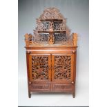 A CARVED ORIENTAL STYLE TABLE CABINET, the pierced fretwork doors opening to three drawers with