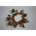 A 9CT GOLD AND YELLOW METAL CHARM BRACELET, charms include a railway lamp, kettle and fish etc.