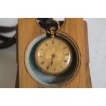 A YELLOW METAL (Marked 18ct) CONTINENTAL FOB WATCH, contained in a folding wooden stand.