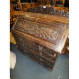 AN ANTIQUE CARVED OAK BUREAU WITH MASK HANDLES - W 93 CM