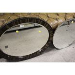 A CIRCULAR BEVEL EDGED WALL MIRROR TOGETHER WITH AN OVAL MIRROR