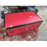 A LARGE RED STUDDED PACKING TRUNK