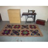 AN IKEA 4 DRAWER MAIN CHEST AN ANTIQUE RUG AND A SINGER HAND SEWING MACHINE IN CAST TABLE.