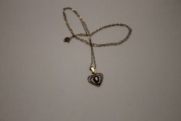 A 9 CT GOLD HEART SHAPED PENDANT SET WITH RED STONE ON A CHAIN