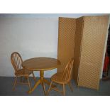 A ROUND DINING SET INCLUDING A TABLE TWO CHAIRS AND A PRIVACY SCREEN.