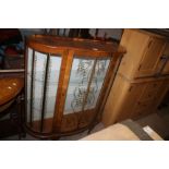 A WALNUT BOWED CHINA CABINET.