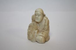 A VINTAGE NETSUKE IN THE FORM OF A KNEELING MAN