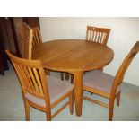 A CIRCULAR EXTENDING DINING TABLE AND FOUR CHAIRS