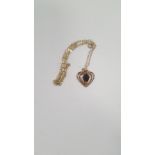 A 9 CT GOLD HEART SHAPED PENDANT SET WITH RED STONE ON A CHAIN