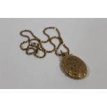 A YELLOW METAL LOCKET ON 9CT GOLD CHAIN