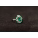 A PLATINUM EMERALD AND DIAMOND DRESS RING, set with a central oval-cut emerald, surrounded by