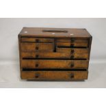 A VINTAGE WOODEN ENGINEERS TOOL CHEST FITTED WITH 8 DRAWERS AND A LIFT OFF FRONT PANEL,