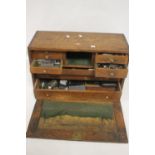 A VINTAGE WOODEN ENGINEERS TOOL CHEST FITTED WITH 8 DRAWERS AND A LIFT OFF FRONT PANEL, with a