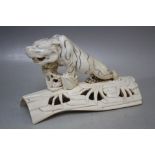 A MEIJI PERIOD CARVED IVORY JAPANESE TIGER ON A PIERCED BRANCH BASE, the tiger with incised stripe