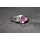 AN 18ct WHITE GOLD PINK SAPPHIRE AND DIAMOND THREE STONE RING, Oval-cut pink sapphire 1.50ct. RBC