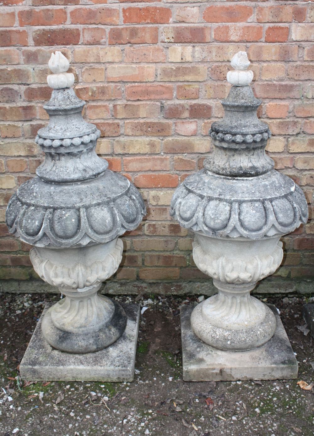 A PAIR OF LARGE STONE PEDESTAL URNS, supported on a squared foot leading to a solid swirling base,