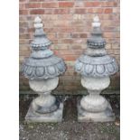 A PAIR OF LARGE STONE PEDESTAL URNS, supported on a squared foot leading to a solid swirling base,