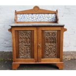 AN ANTIQUE MARBLE TOPPED OAK WASHSTAND, the two doors with Gothic carved detail, with tile back,