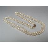 A DOUBLE STRAND HAND KNOTTED CULTURED PEARL NECKLACE WITH 9CT GOLD CLASP, shortest strand approx L