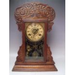 AN ANTIQUE OAK 'GINGERBREAD' MANTLE CLOCK OF TYPICAL FORM, with paper label to reverse, key,