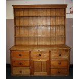 A LARGE ANTIQUE PINE KITCHEN DRESSER, having enclosed plate rack, the base with an arrangements of