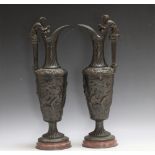 A PAIR OF BRONZE BACCHUS EWERS, seeing Bacchus squeezing a bunch of grapes into the ewer as he