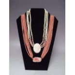 A TEN STRAND CORAL BEAD NECKLACE, with yellow metal mounted floral clasp carved in high relief,