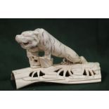 A MEIJI PERIOD CARVED IVORY JAPANESE TIGER ON A PIERCED BRANCH BASE, the tiger with incised stripe