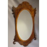 A 19TH CENTURY MAHOGANY SHAPED WALL MIRROR, the oval glass within a cross banded border, with furthe