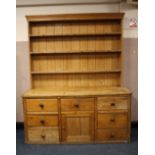 A LARGE ANTIQUE PINE KITCHEN DRESSER, having enclosed plate rack, the base with an arrangements of