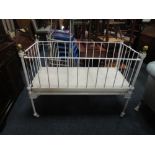 AN ANTIQUE METAL AND BRASS BABYS COT BED WIT DROP DOWN SIDE, W 128 cm